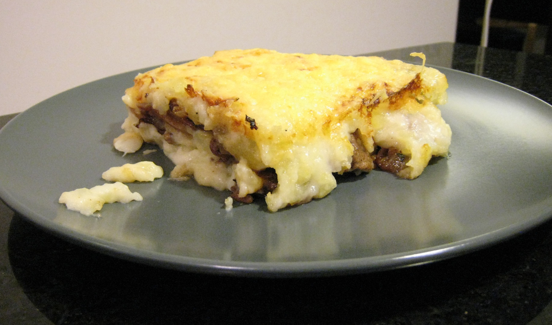 Une portion de hachis parmentier sur une assiette gris taupe