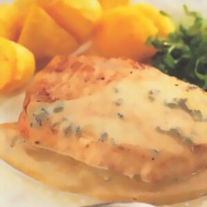 Assiette gourmande mettant en avant une mignonette de porc nappée d'une sauce crémeuse au roquefort, décorée de fines herbes. Le plat est accompagné de pommes de terre dorées et d'une touche de verdure en arrière-plan, avec une présentation élégante et appétissante