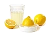 Un verre de jus de citron, à côté d'un citron entier, d'un demi-citron et d'un demi-citron posé sur un presse-fruit